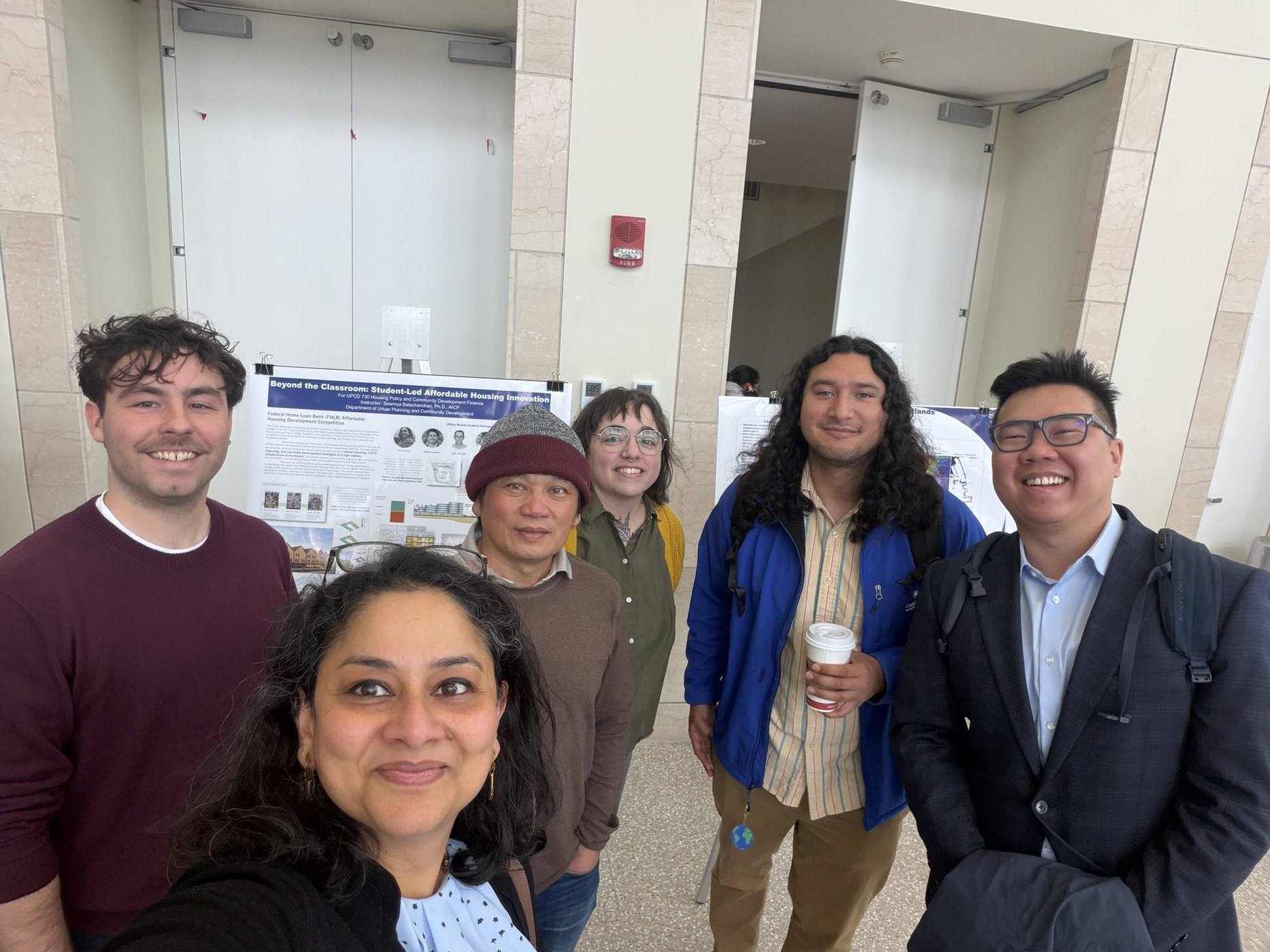 Students and faculty standing with affordable housing project posters